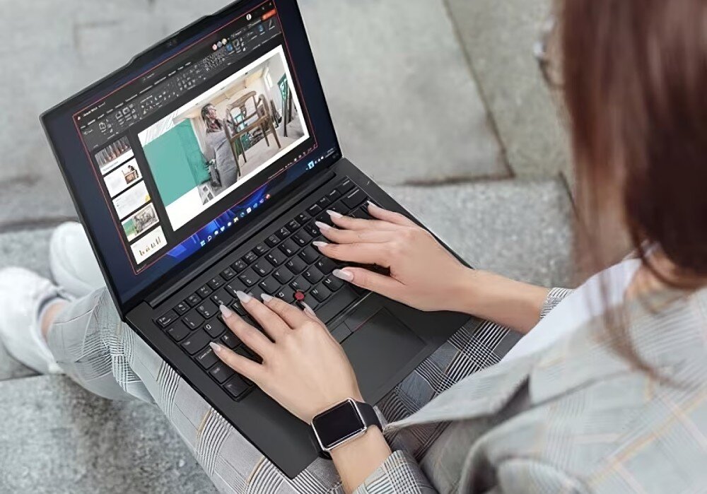 Osoba wpisująca tekst na laptopie Lenovo ThinkPad E14 podczas pracy na schodach, wyświetlacz pokazujący prezentację -  funkcje skróty TrackPoint