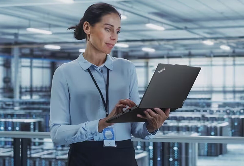 Kobieta pracująca na laptopie Lenovo ThinkPad E14 w jasnym biurze, skupiona na ekranie -  ochrona danych zabezpieczenia