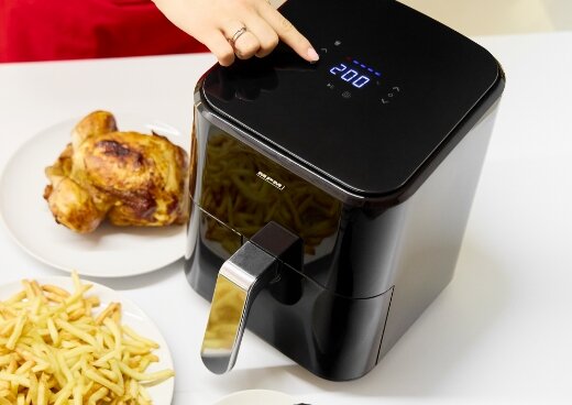 Frytownica MFR-11 na kuchennym blacie. Osoba wskazuje palcem na przyciski urządzenia.