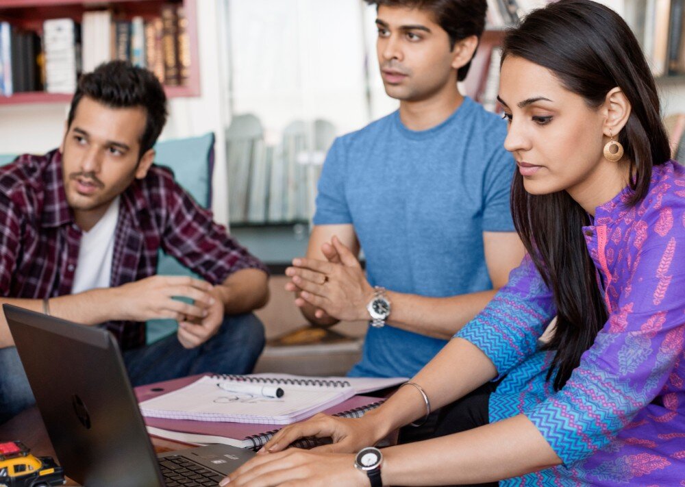 Laptop HP EliteBook 630 G11 Trzy osoby, dwóch mężczyzn i kobieta, współpracujący przy laptopie podczas spotkania w pomieszczeniu z regałem w tle, łączność Wi-Fi, Bluetooth 5.3