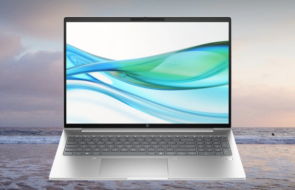 Laptop HP ProBook 445 G11 - srebrny laptop otwarty na tle plaży i morza. Na ekranie wyświetla się abstrakcyjna grafika w odcieniach zieleni i błękitu, przedstawienie podzespołów procesora pamięci i dysku