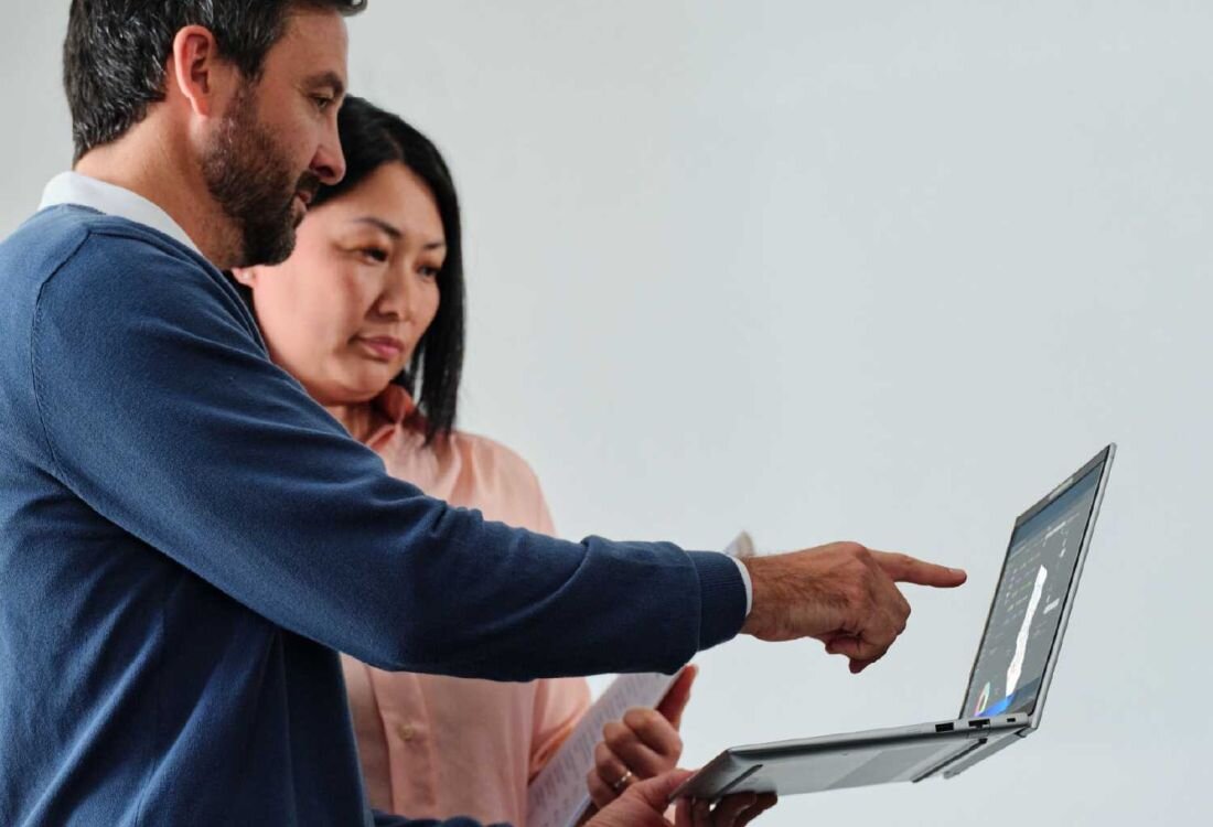 Dwóch mężczyzn współpracujących przy laptopie HP EliteBook 665 G11, jeden wskazuje na ekran podczas prezentacji, drugi słucha, w tle kobieta w różowej koszuli, środowisko biurowe. - procesor Intel Core Ultra   