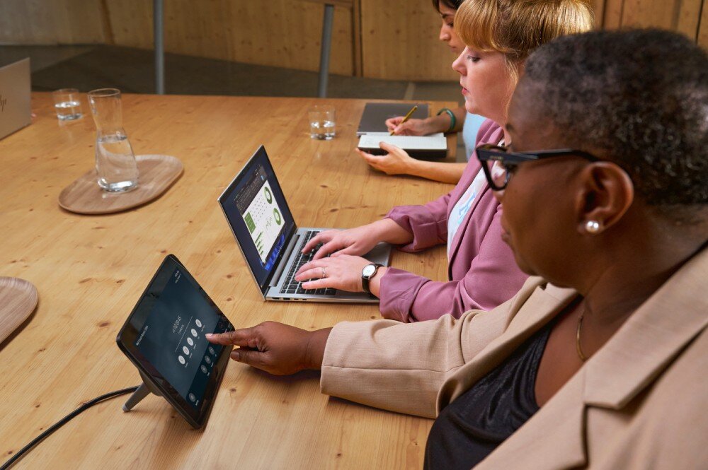 Laptop HP EliteBook 1040 G11 Grupa osób siedzących przy stole konferencyjnym. Kobieta w jasnej marynarce obsługująca dotykowy panel sterowania, a inne osoby pracujące na laptopach, łączność Wi-Fi 6E, Bluetooth 5.3