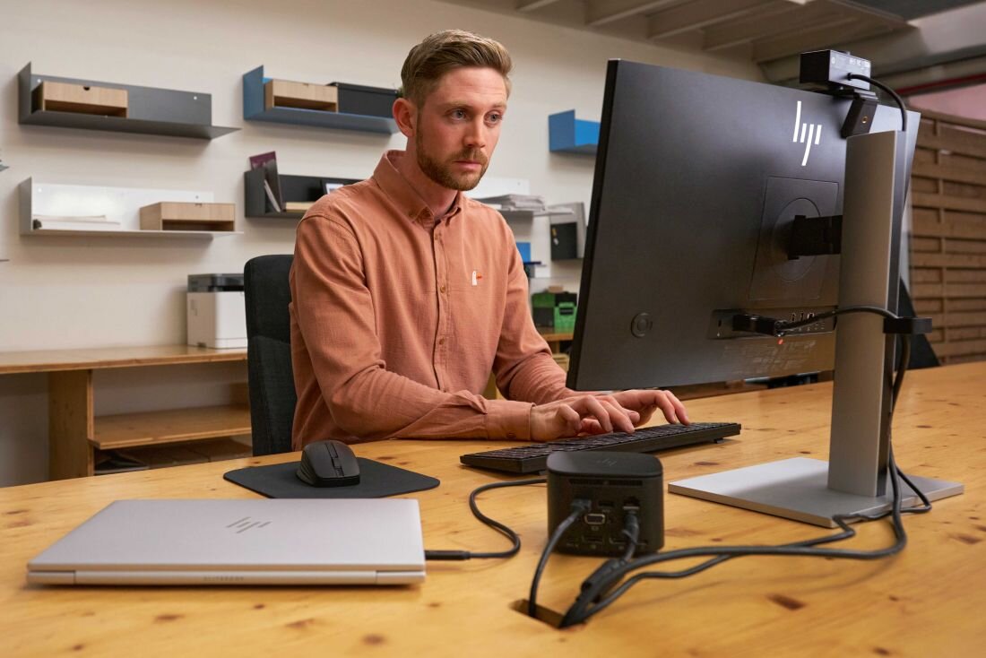 Laptop HP EliteBook 860 - Mężczyzna przy biurku z laptopem HP EliteBook 860 i komputerem, skupiony na pracy.