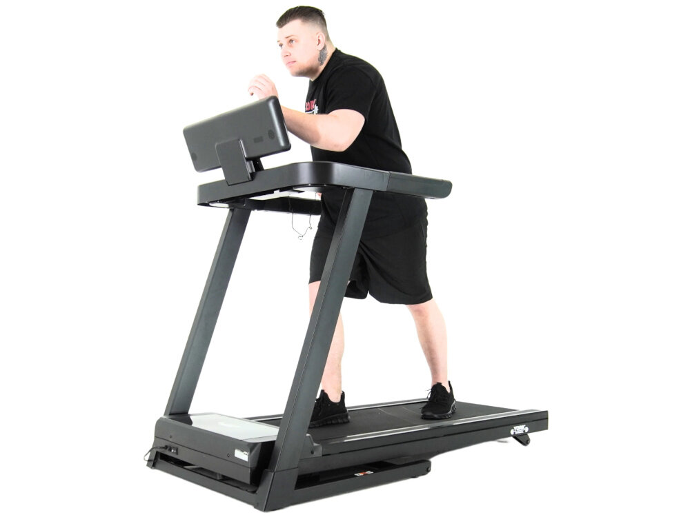 Bieżnia elektryczna YORK FITNESS HT5 1470W 18km-h białe tło osoba w czarnym stroju sportowym biegnie na bieżni dla użytkowników o wadze do 110 kg stabilna rama bezpieczeństwo podczas intensywnych treningów równomierne rozłożenie obciążenia minimalizuje ryzyko wypadków