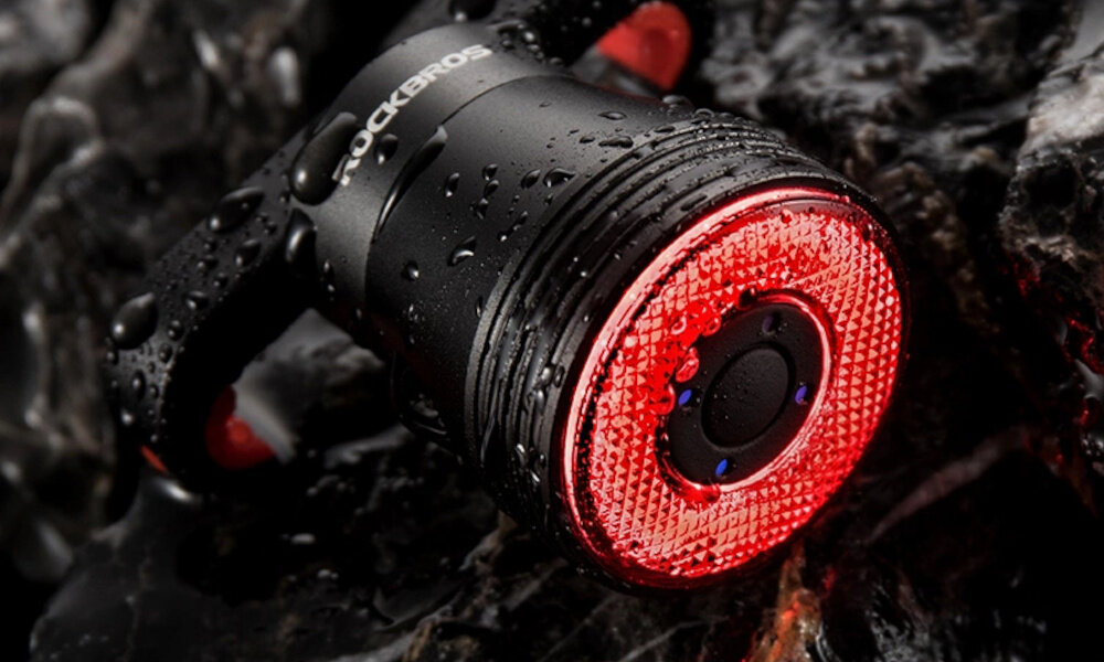 Lampka rowerowa ROCKBROS Q5 157347 droga lampka leży na drodze jest mokra krople wody dołączony kabel USB-C/USB-A bateria ma aż 400 mAh pojemności wodoodporny (IP65)