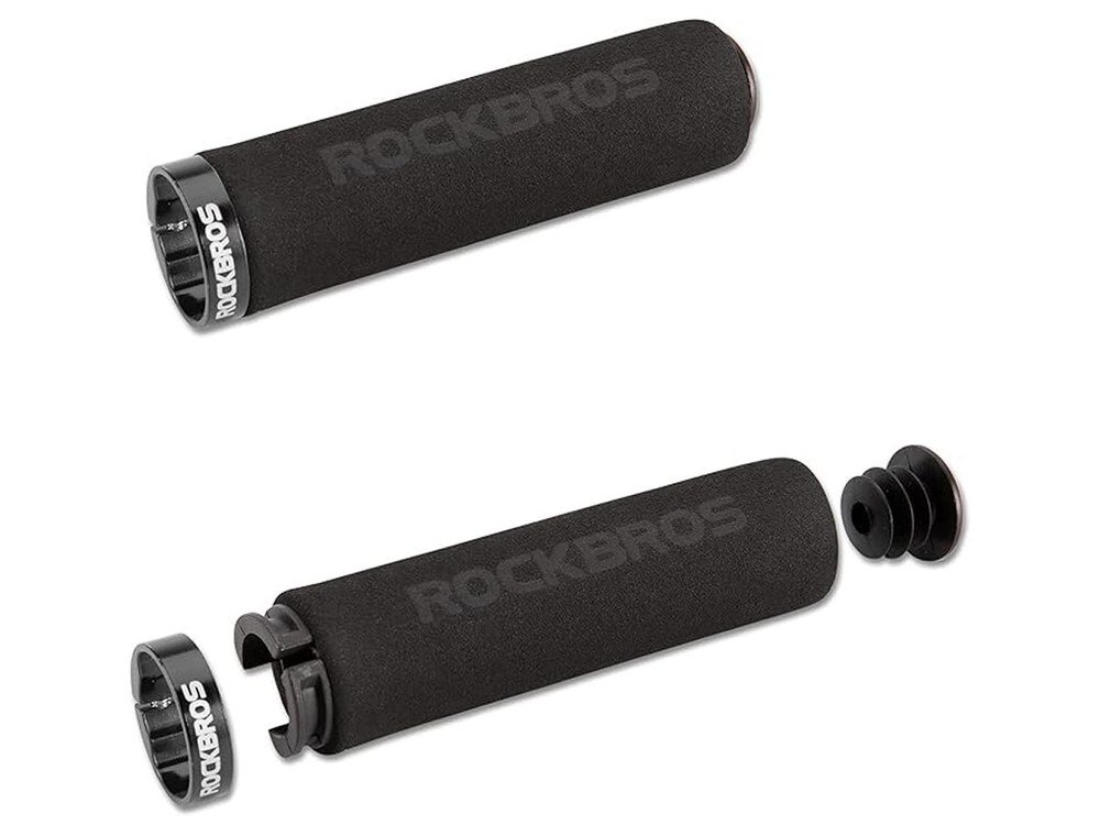Na obrazie widoczne są dwa czarne chwyty do kierownicy z logo \'ROCKBROS\' na metalowych pierścieniach. Jeden z chwytów jest rozłożony, ukazując wewnętrzne elementy montażowe.