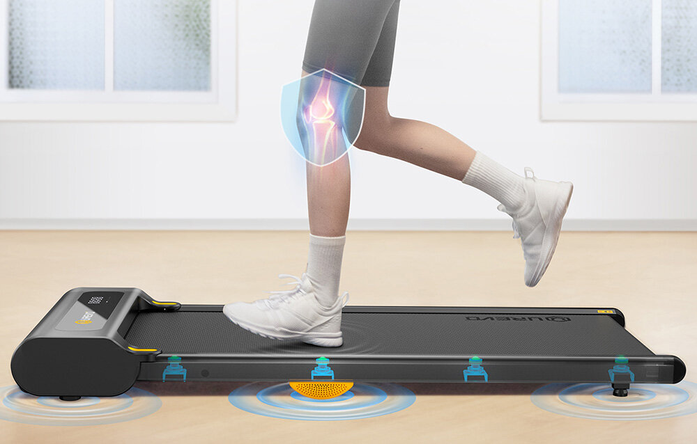 Bieżnia elektryczna UREVO Spacewalk SP1 Lite 1677W 6km-h pokój osoba korzysta z bieżni pokazane miejsca amortyzujące pracę silnik o mocy 2,25 KM prędkość od 1 do 6 km/h wydajna praca obciążenie do 120 kg