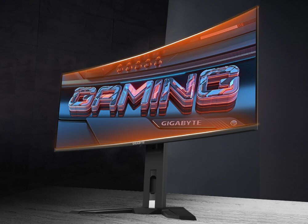 Monitor GIGABYTE MO34WQC Zakrzywiony monitor wyświetlający napis 'GAMING' w trójwymiarowym stylu na tle ciemnego pomieszczenia, zakrzywienie, konstrukcja, ekran