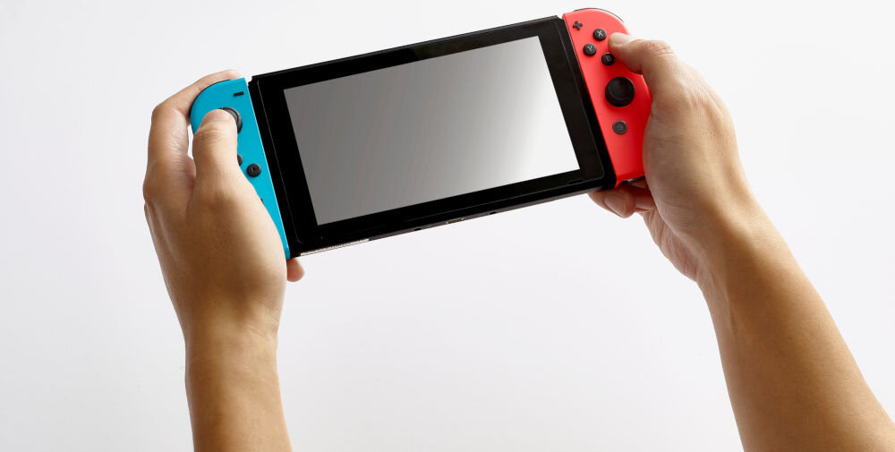 Karta pamięci SANDISK MicroSDXC 64GB do Nintendo Switch Yoshi Edition konsola trzymana w rękach na białym tle miejsce dla gier prędkość odczytu