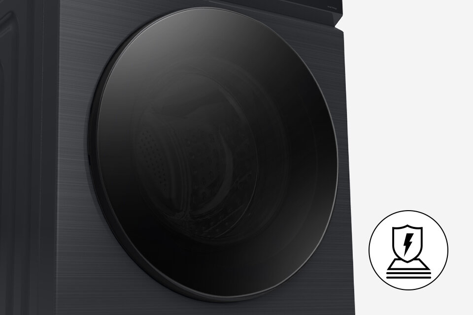 Obraz przedstawia czarną pralko-suszarkę z dużymi, okrągłymi drzwiami. Obok znajduje się ikona z tarczą i symbolem błyskawicy.