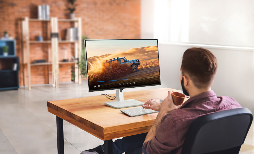 Monitor LENOVO L27h-4A 27 cali 2560x1440px IPS 100Hz 1 ms [MPRT] prezentacja monitora w pokoju mężczyzna siedzący przy biurku z kubkiem kawy