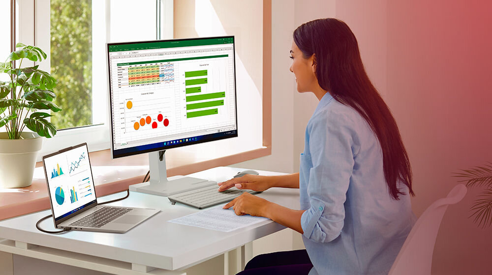 Monitor LENOVO L27q-4A 27 cali 2560x1440px IPS 100Hz 1 ms [MPRT] prezentacja monitora w pokoju w trakcie pracy dziewczyna siedząca przy biurku cienkie ramki szeroka przestrzeń robocza skupienie praca z wieloma oknami smukły biuro dom