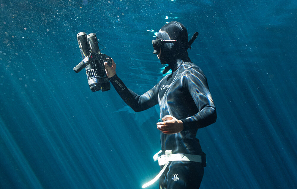 Skuter podwodny WAYDOO Subnado Czarny + zestaw startowy osoba w piance w głębinach wody w dłoni trzyma skuter eksploracja pod wodą pasja hobby sport wodny