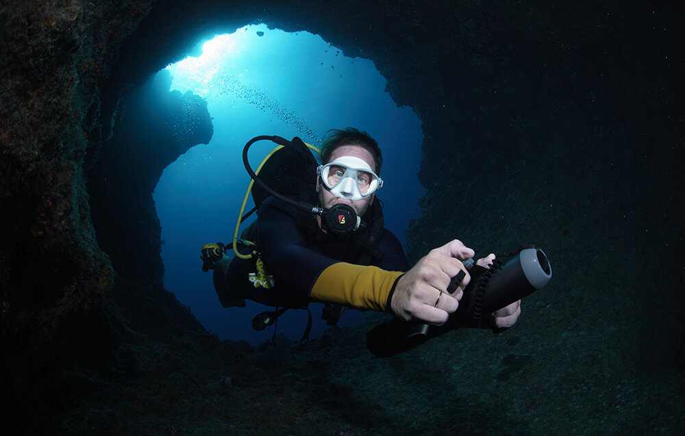 Skuter podwodny WAYDOO Subnado Czarny + zestaw osoba w piance w głębinach wody w dłoni trzyma skuter płynie eksploracja wodnych przestrzeni lekka konstrukcja dla dorosłych i dzieci opatentowana technologia pełne naładowanie zajmuje jedynie 1,2 h czas działania do 56 min funkcja powerbanku z mocą do 100 W