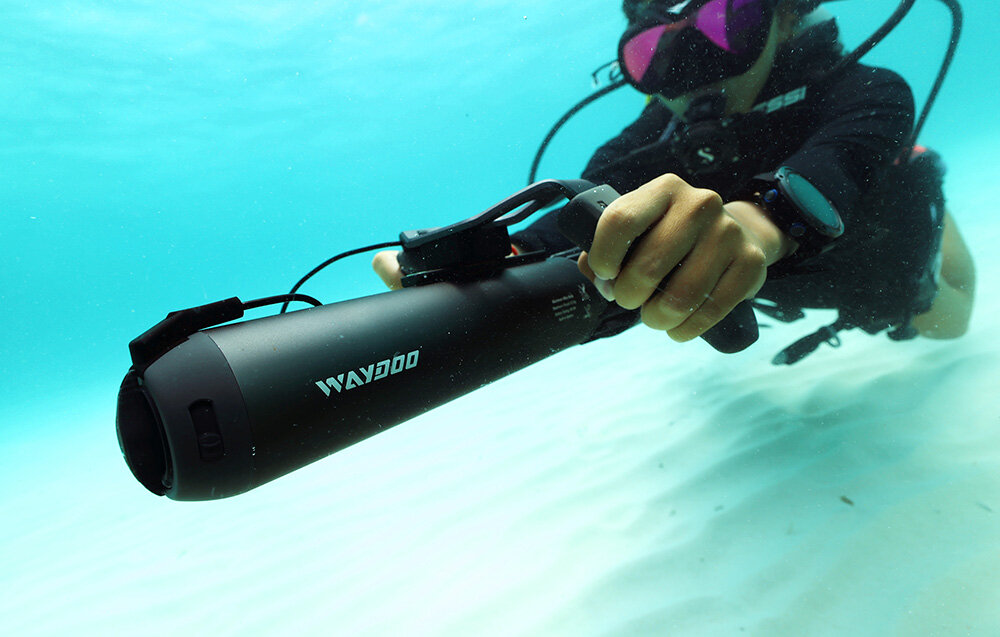 Skuter podwodny WAYDOO Subnado Czarny + zestaw startowy osoba w piance w głębinach wody w dłoni trzyma skuter płynie mocowanie (1/4-20 UNC) do trzech akcesoriów