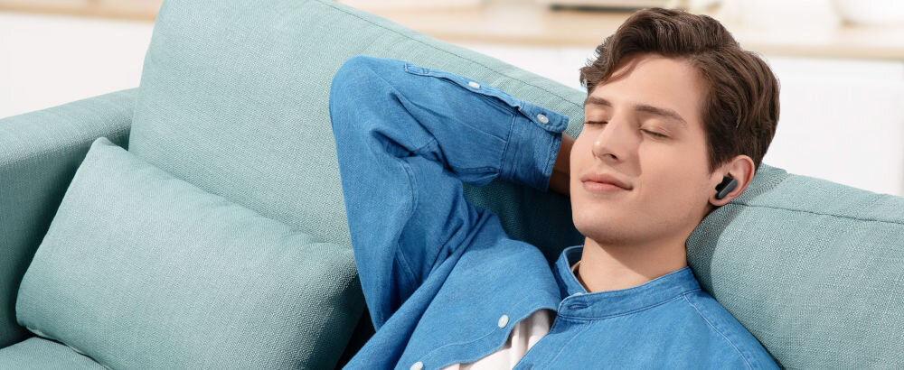 Słuchawki dokanałowe SOUNDCORE R50i v2 biały szum relaks skupienie sen aplikacja, osoba z założonymi słuchawkami dokanałowymi siedząca na kanapie