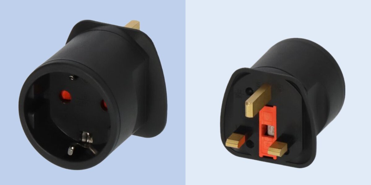 Na obrazie widoczny jest czarny adapter podróżny z trzema bolcami z jednej strony i dwoma otworami z drugiej. Adapter jest przedstawiony na jasnoniebieskim tle.