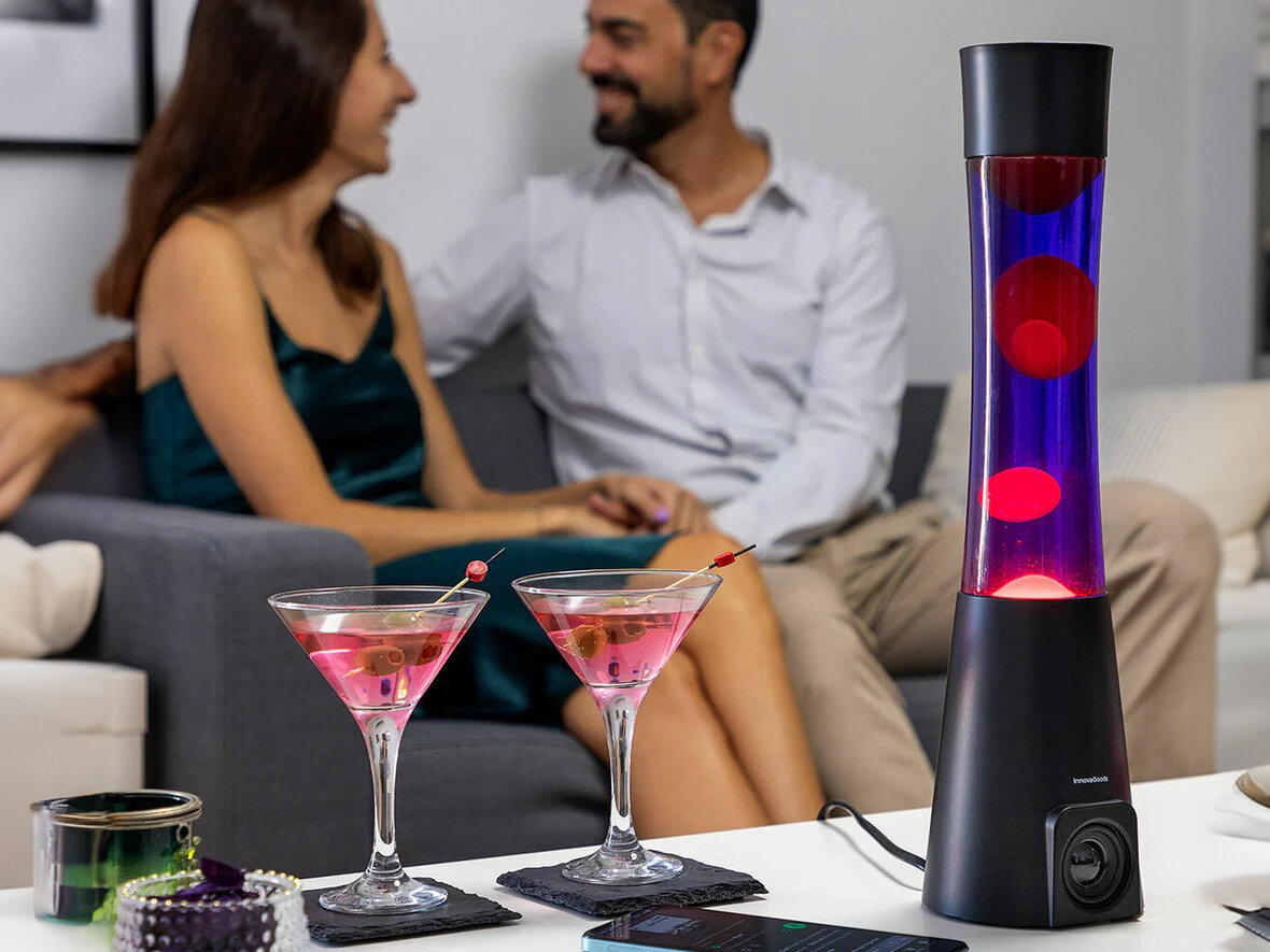 Lampka nocna INNOVAGOODS Lava Maglamp z głośnikiem Czarny, retro, design, szkło, aluminium, Lampa lawa i dwa kieliszki z drinkami na stole.