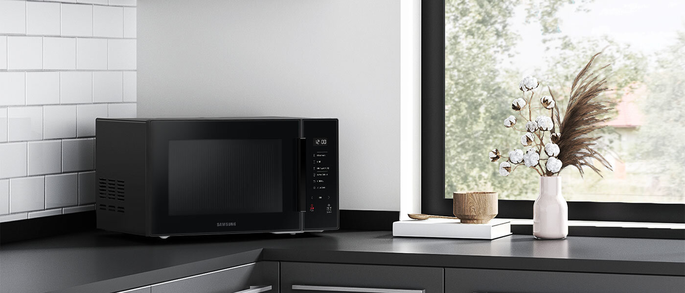 Zdjęcie kuchenki mikrofalowej Samsung MG30T5018CK z frontem z czarnego szkła stojącej na blacie nowoczesnej kuchni