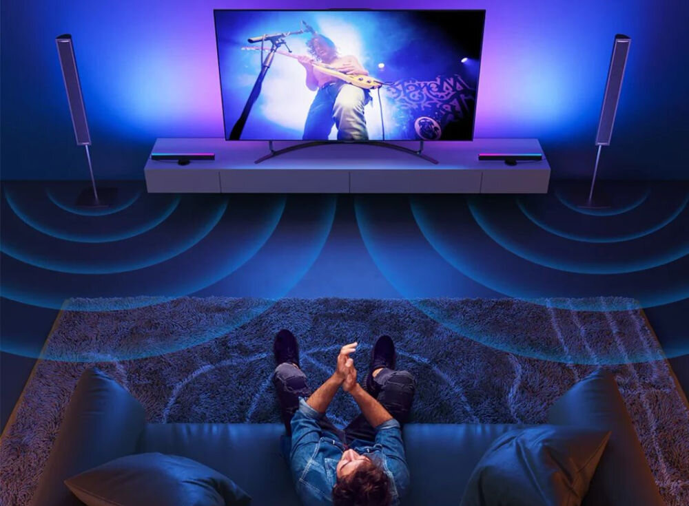 Lampa LED GOVEE H6046 Wi-Fi/Bluetooth osoba siedząca na kanapie widok od góry na regale telewizor i lampy imitacja dźwięku technologia RGBIC ożywienie domowej rozrywki