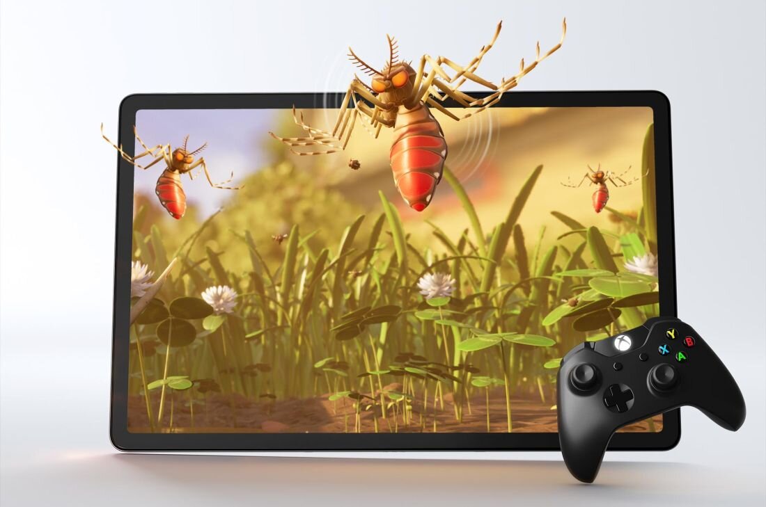 Tablet wyświetla animowaną scenę z owadami unoszącymi się nad trawą. Obok tabletu znajduje się czarny kontroler do gier.