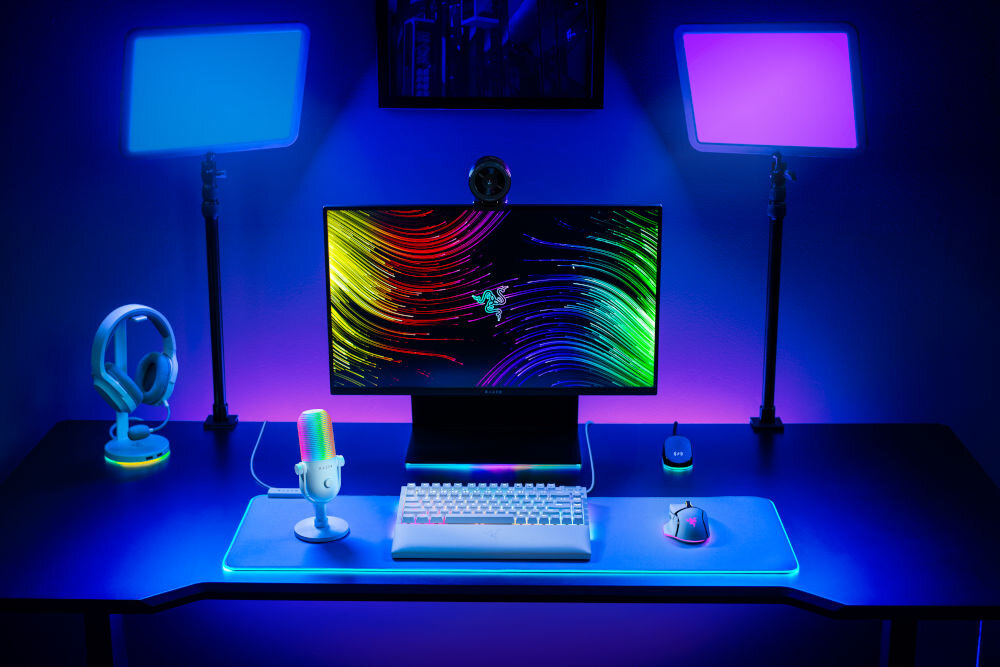 Mikrofon RAZER Seiren V3 Chroma Superkardioidalny Biały prezentacja mikrofonu na biurku w pokoju gamingowym w tle kolorowe ledy nadające klimatu światła automatyczny limiter wzmocnienia dotykowy czujnik mapowanie poleceń świetna opcja dla graczy