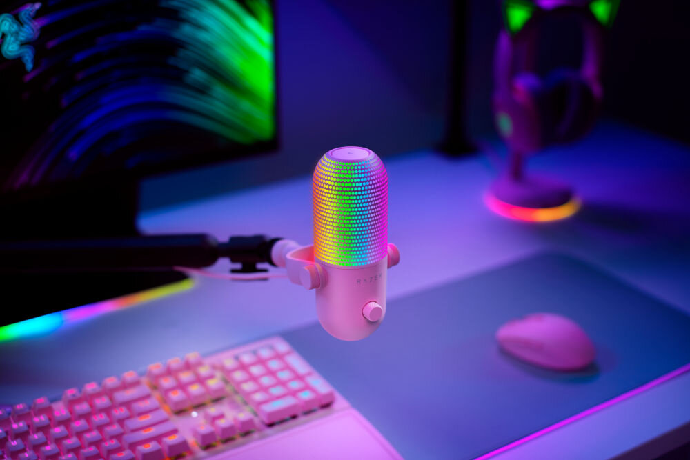 Mikrofon RAZER Seiren V3 Chroma Superkardioidalny Różowy prezentacja mikrofonu na biurku w pokoju gamingowym w tle kolorowe ledy superkardioidalna charakterystyka kierunkowa mikrofonu tłumienie niepożądanych dźwięków czyste wyraziste brzmienie wysoka jakość transmisji pasmo przenoszenia 20 - 20000 Hz poziom ciśnienia akustycznego 110 dB czułość -34 dB