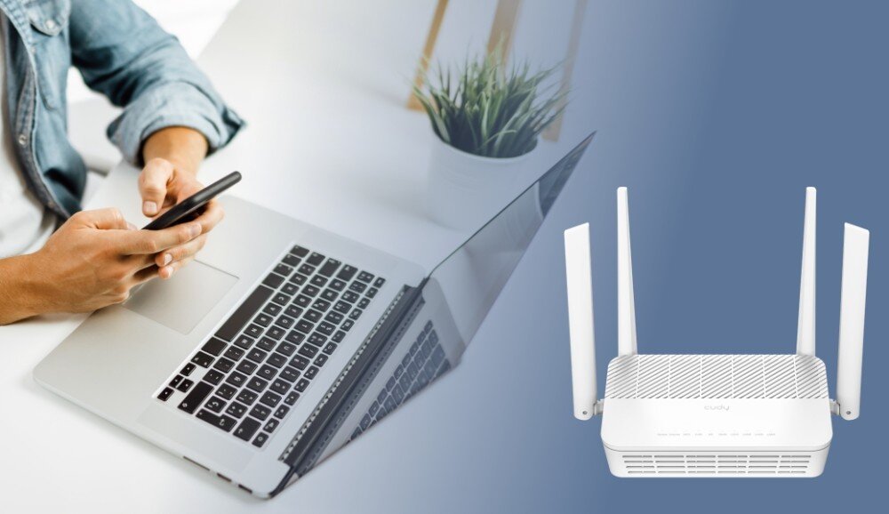 Router CUDY WR3000S Osoba trzymająca smartfon nad otwartym laptopem na białym biurku. Po prawej stronie znajduje się biały router z czterema antenami, opis