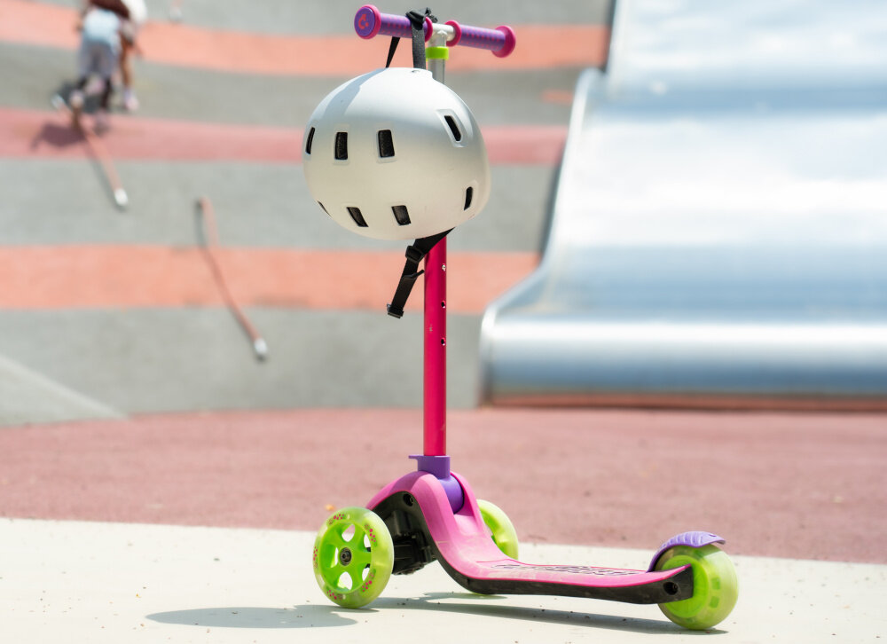 Hulajnoga dla dzieci TRUNKI Mała Różowy skatepark hulajnoga stoi na drodze w tle kolorowa ściana nauka jazdy środek transportu nauka koordynacja radość pasja