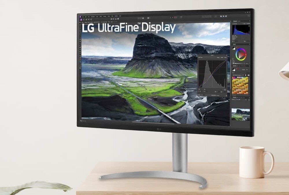 Monitor LG UltraFine 32UQ850V-W Monitor na biurku z wyświetlonym edytorem graficznym i zdjęciem krajobrazu górskiego z zielonymi dolinami oraz histogramem i kołem barw po prawej stronie ekranu, opis