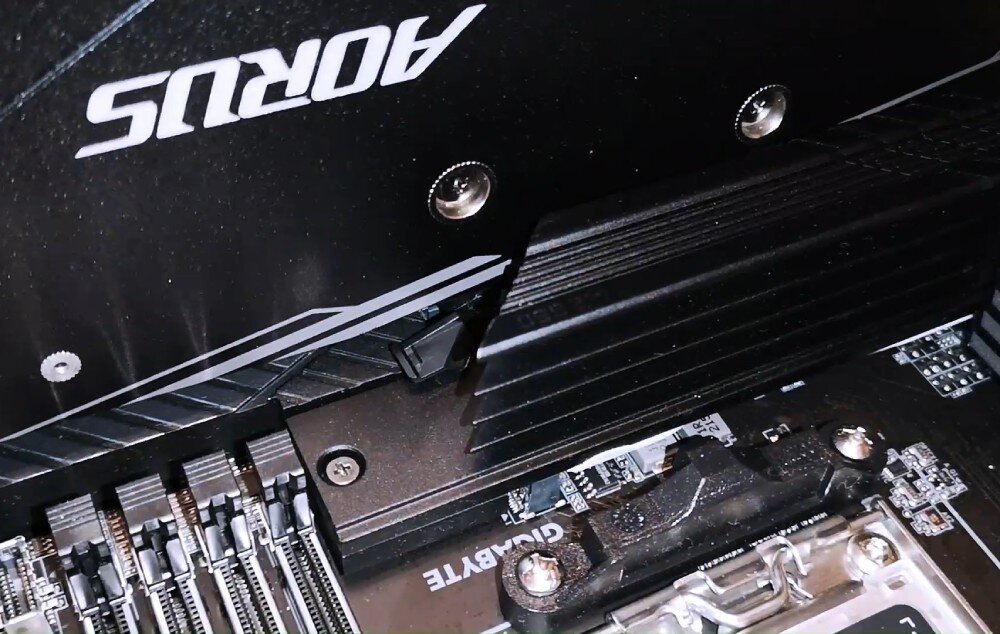 Płyta główna GIGABYTE B760M D3HP Zdjęcie przedstawia fragment zamontowanej płyty głównej z grafiką AORUS. Widać jeden z radiatorów oraz część slotów na pamięć RAM, ułatwienia montażu