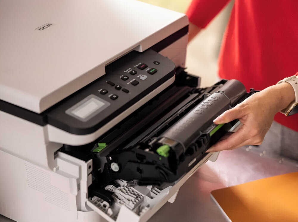 Urządzenie wielofunkcyjne BROTHER DCP-B7620DW Automatyczny druk dwustronny, Wi-Fi prezentacja urządzenia podczas korzystania przez kobietę prędkość druku tryb monochromatyczny eliminacja długiego czasu oszekiwania czas potrzebny na wydruk pierwszej strony