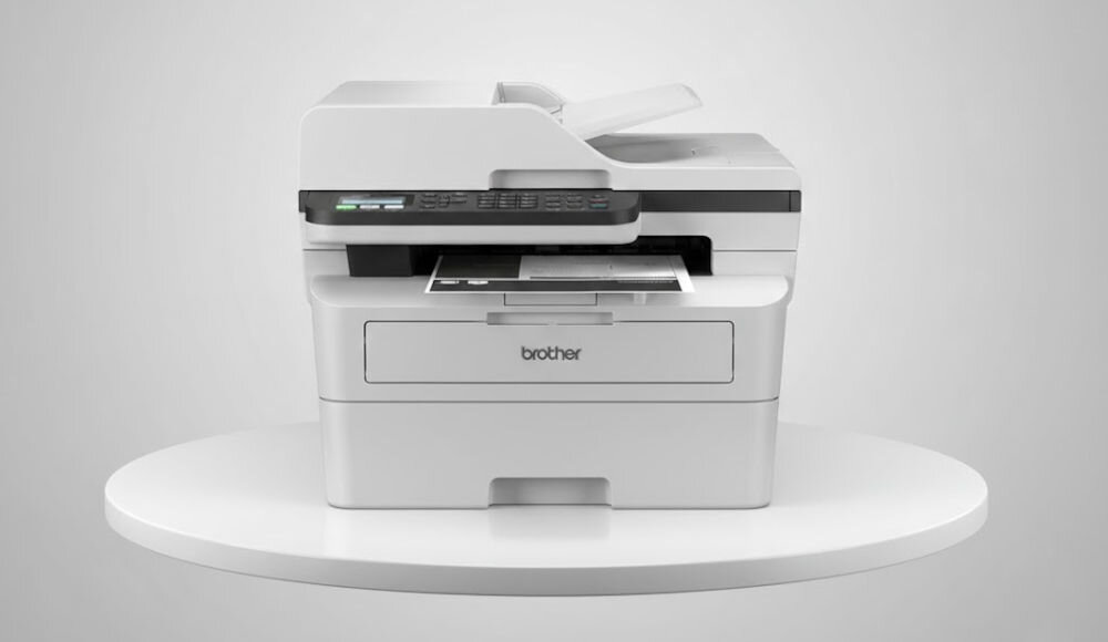 Urządzenie wielofunkcyjne BROTHER MFC-B7800DN Automatyczny druk dwustronny prezentacja urządzenia na podeście na jasnym tle interfejs USB sprawne przesyłanie danych prosta konfiguracja standard Hi-Speed USB 2.0 efektywna obsługa dokumentów