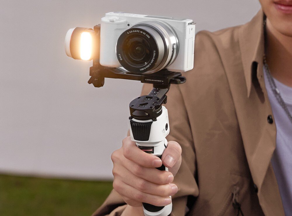 Gimbal ZHIYUN Crane M3S Combo osoba trzymająca gimbala z widoczną lampką, która świeci ciepłym światłem lampka jasność regulowana temperatura