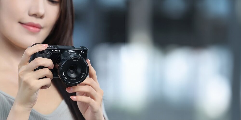 Obiektyw Ulanzi 27 mm f/2,8 AF na aparacie trzymanym przez modelkę
