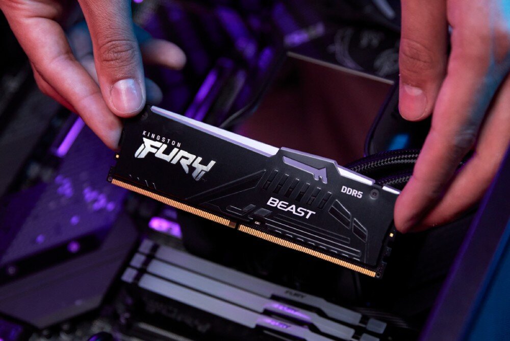 Pamięć RAM KINGSTON Fury Beast RGB Dłonie osoby montującej moduł pamięci w gnieździe na płycie głównej
