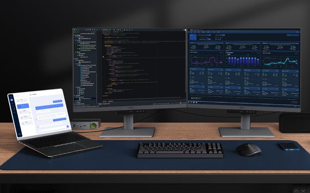 Monitor BENQ RD280U Dwa monitory ustawione obok siebie na biurku. Na lewym ekranie środowisko kodowania, na prawym panel analityczny z wykresami. Po lewej laptop z aplikacją czatu, porty, wejścia, przełącznik KVM