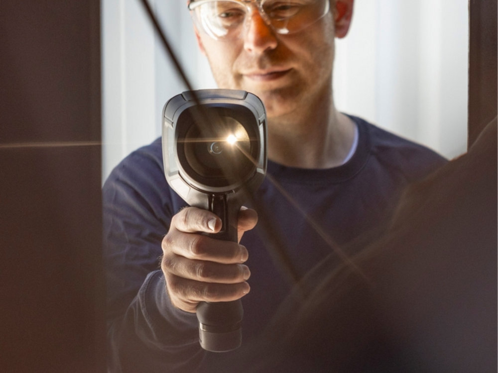 FLIR E8 Pro FLIR E8 Pro 1-Touch Level/Span dopasowującą poziomy kontrastu Narzędzia zgodne z NFPA 70B różnicę temperatur ΔT - kamera w ręku mężczyzny od przodu