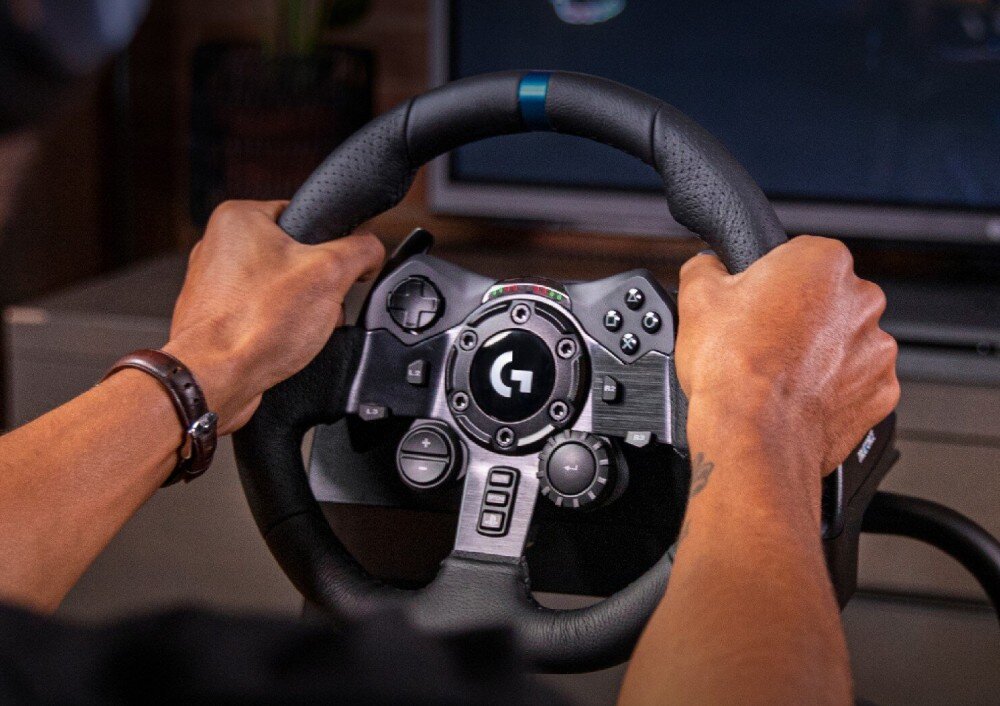 Kierownica LOGITECH G923 + Shifter Bundle Mężczyzna trzymający w dłoniach kierownicę wyścigową podczas gry z widocznymi diodami LED na obudowie