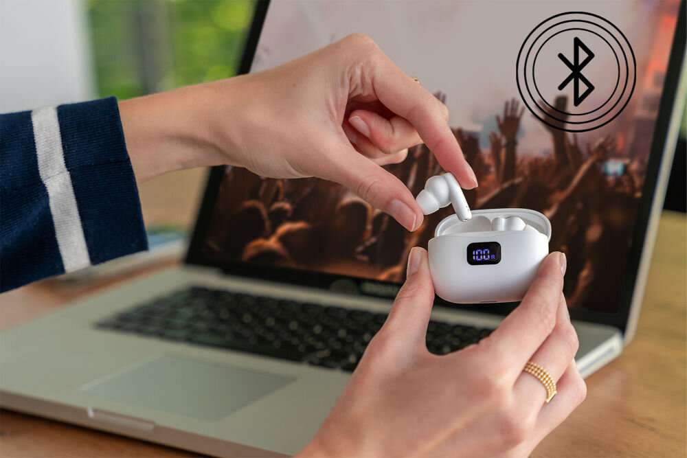 Słuchawki dokanałowe XMUSIC XTW500W Czarno etui ładujące do słuchawek XMUSIC XTW500W z cyfrowym wskaźnikiem stanu baterii L/R na tle laptopa.