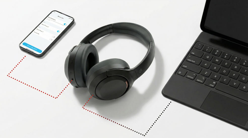 Na białym tle znajdują się czarne słuchawki nauszne obok smartfona i laptopa. Smartfon wyświetla ekran z ustawieniami Bluetooth, a między urządzeniami widoczne są przerywane linie sugerujące połączenie.