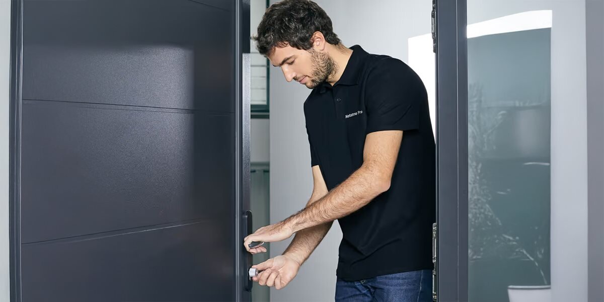 Klucz do zamka NETATMO NDL-K1U, smart door lock, kontrola, dostęp, montaż, mężczyzna obsługuje zamek i klucz przy drzwiach