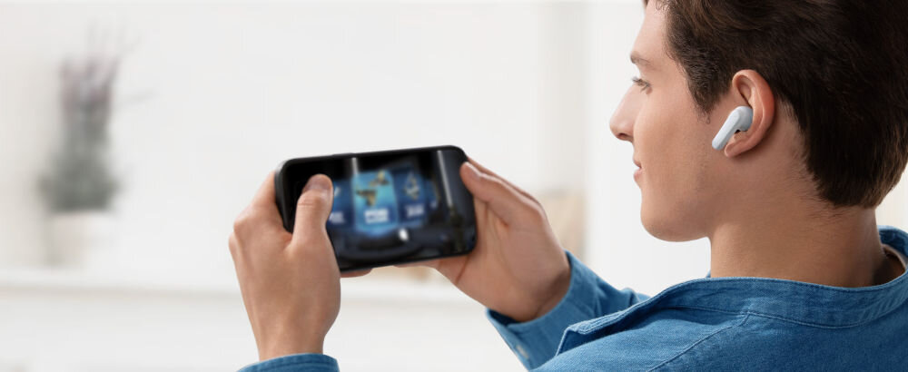 Słuchawki dokanałowe SOUNDCORE R50i v2 tryb gry aplikacja ulepszone efekty dźwiękowe gaming, osoba z założonymi słuchawkami dokanałowymi trzymająca smartfon w rękach