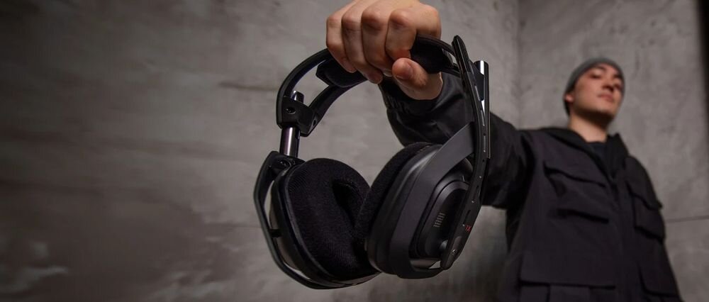 Słuchawki LOGITECH Astro A50 (Gen 5) PLAYSYNC AUDIO przełączanie PS5 PC Xbox bezprzewodowem, osoba trzymająca słuchawki w ręku