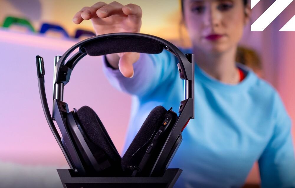 Słuchawki LOGITECH Astro A50 (Gen 5) stacja Click-In 24 godziny pracy DSP 7 rdzeni, słuchawki w stacji bazowej, osoba wyciągająca rękę po słuchawki