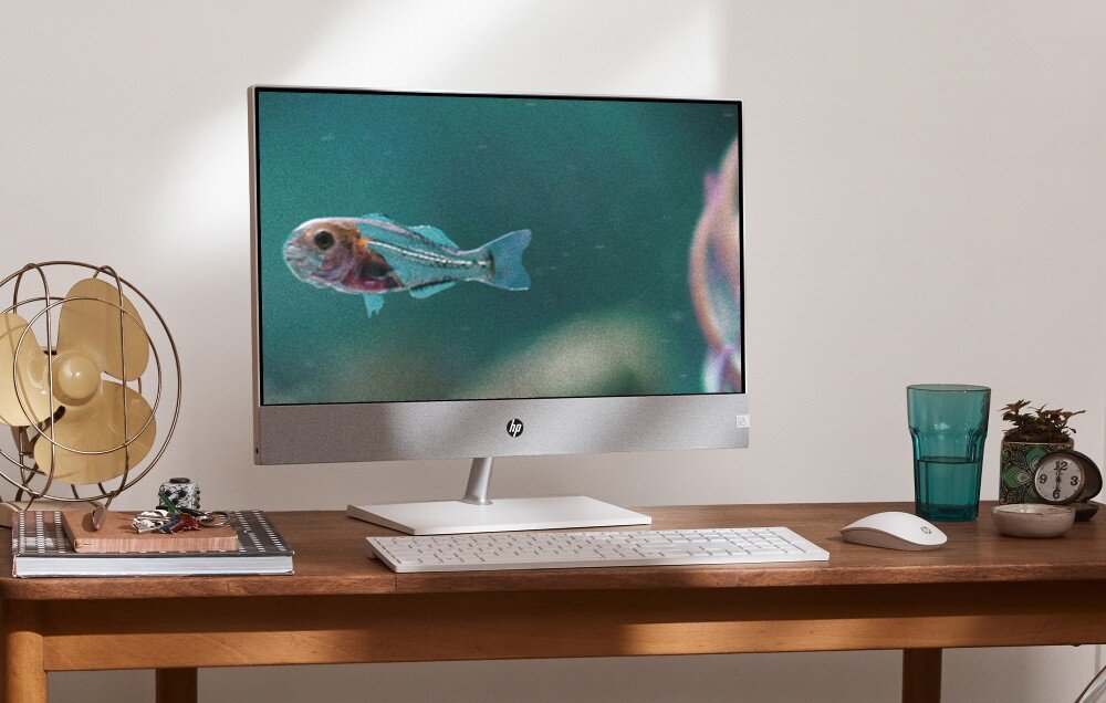 Komputer HP Pavilion 27-ca2092nw Komputer typu all-in-one stoi na biurku, na ekranie wyświetlony jest obraz ryby w wodzie, obok znajdują się klawiatura, mysz i szklanka, ekran, rozdzielczość, obudowa