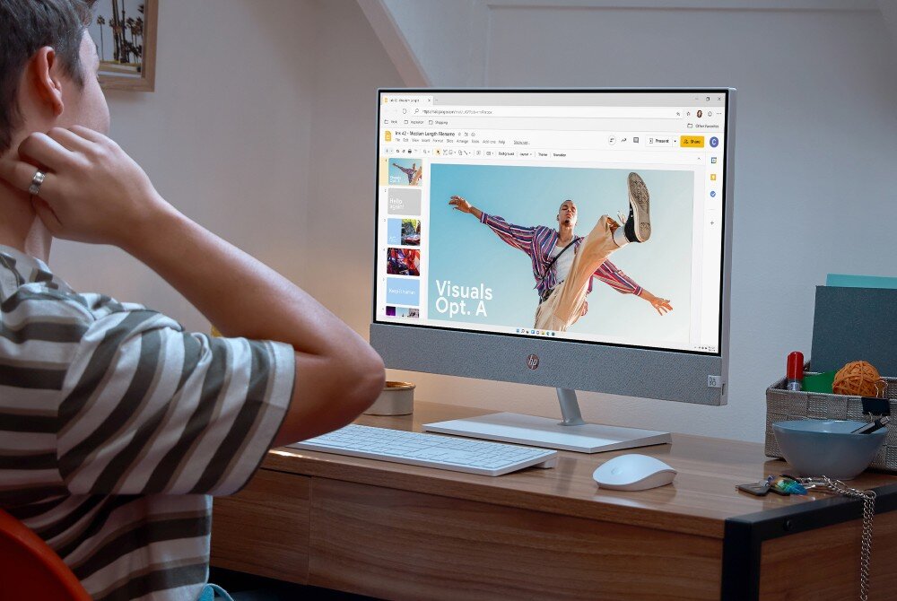 Komputer HP Pavilion 27-ca2092nw Osoba siedzi przy biurku i patrzy na ekran komputera typu all-in-one, na którym otwarta jest prezentacja z napisem 'Visuals Opt. A', procesor, rdzenie, pamięć, układ graficzny