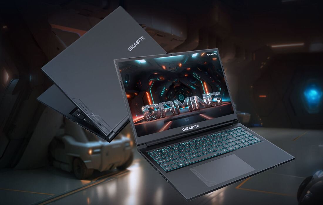  Laptop GIGABYTE G6 z otwartym ekranem wyświetlającym futurystyczną scenę gry z pomarańczowymi i niebieskimi efektami świetlnymi w kosmicznym tunel  