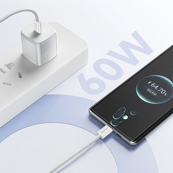 Na obrazie widać czarny smartfon podłączony do białego kabla USB-C, który jest wpięty do białej ładowarki w listwie zasilającej. Na ekranie telefonu widoczny jest wskaźnik ładowania z napisem \'64.70%\', a obok znajduje się duży napis \'60W\'.